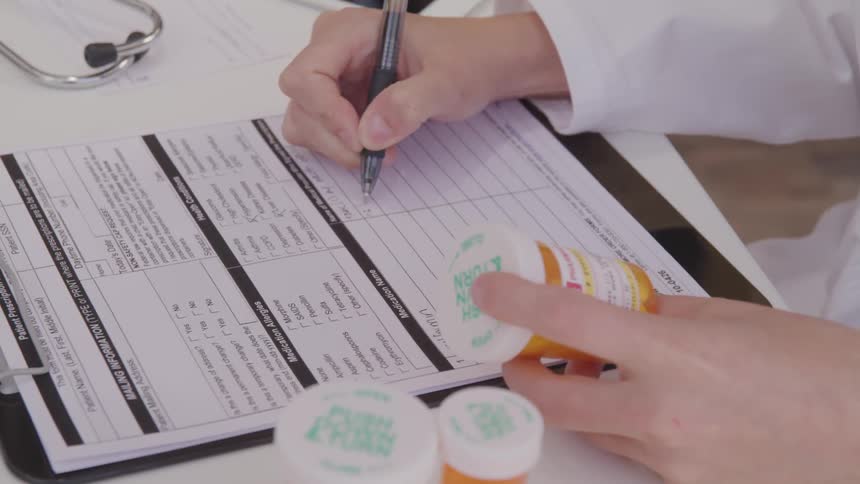 A pharmacist writes out the details of a prescription drug