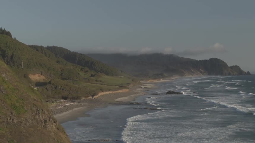 Waves crash against shore near cliffs and road