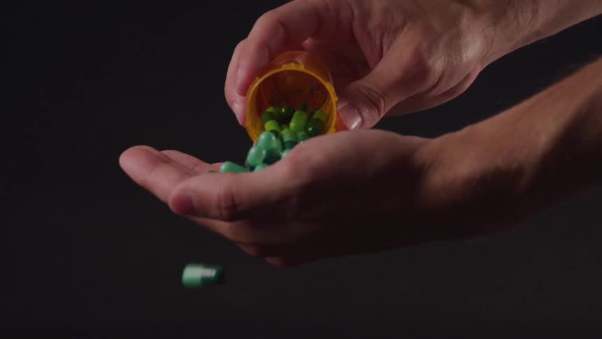 A person pours pills out of a container into their hand