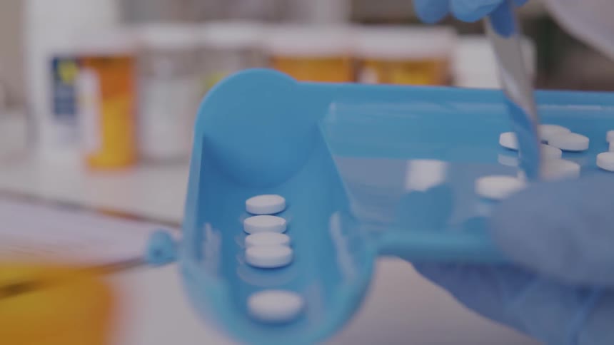 A pharmacist counts pills into a shoot