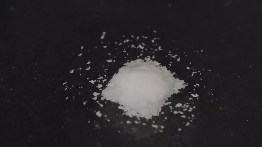 White granules bubbling out of a pile into the surrounding water