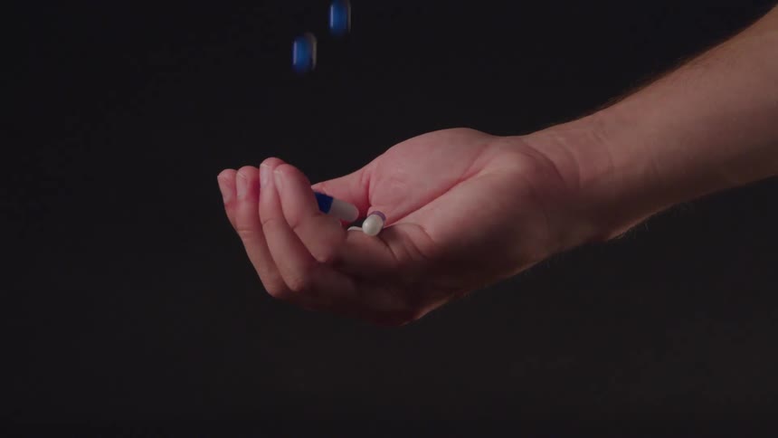 A person is holding their hand out to catch pills
