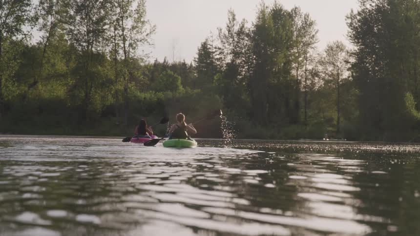 Two woman canoeing in a lake with trees and the sky in the background