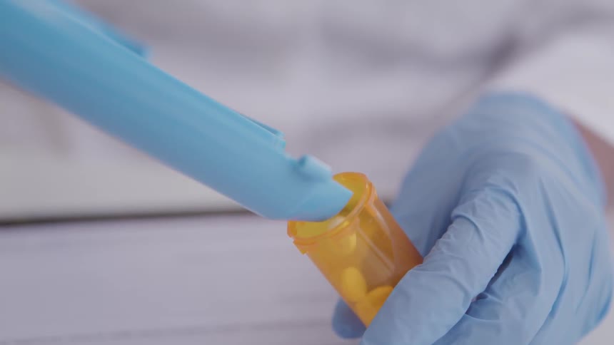 A person is putting pills into a bottle