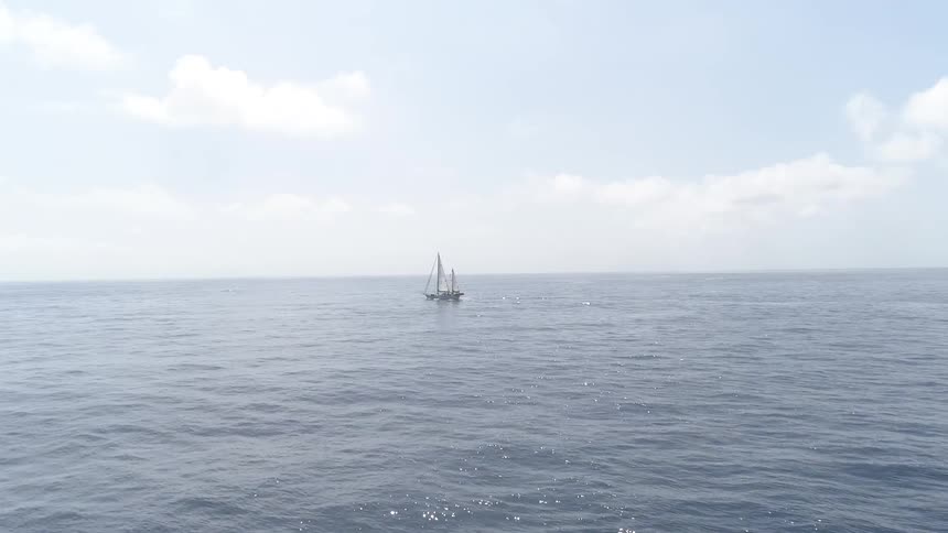 A sailboat sits alone in vast ocean water