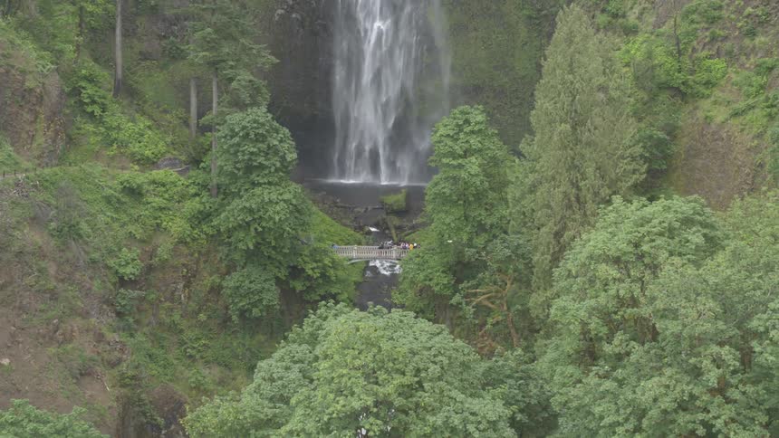 A waterfall cascades down near a bridge