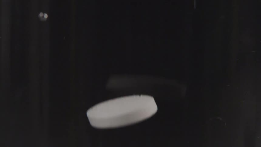 White tablets being dropped against a black backdrop
