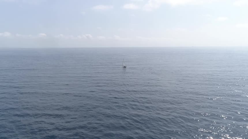 The boat travels over the ocean waves under the sunny sky