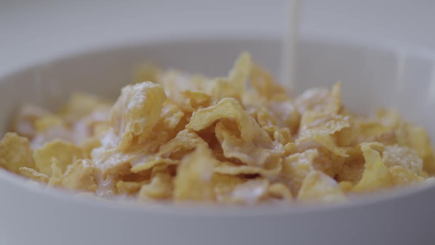 Milk is being poured into a bowl of cereal