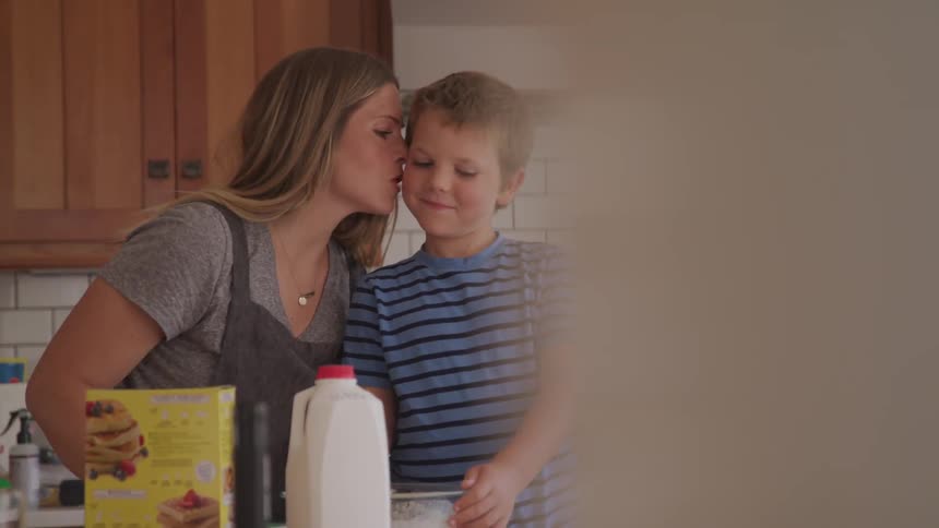 A mother and son mix pancake batter together in a kitchen