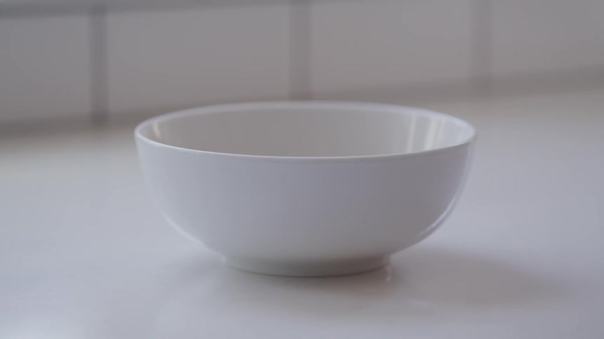 Cereal poured into a white bowl sitting on a white surface
