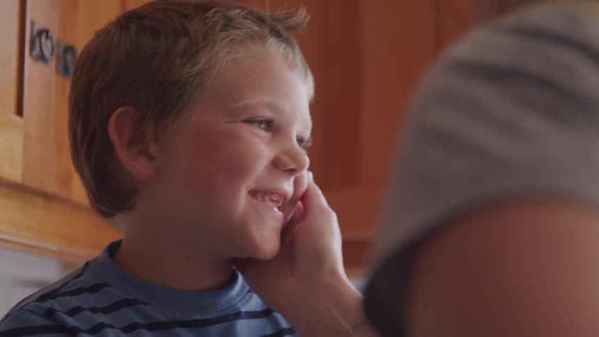 A woman leans in and kisses a boy on the cheek