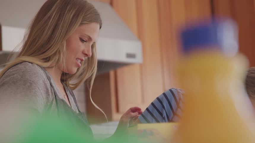 A mother and son cook prepare food together in a kitchen