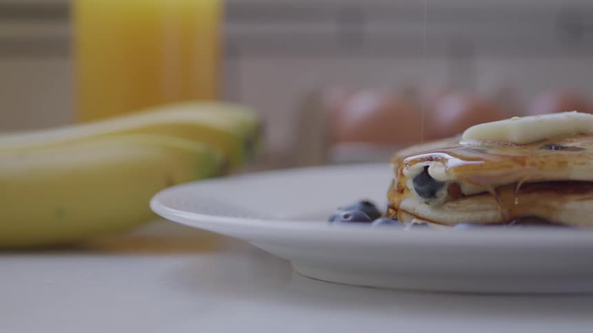 Syrup being poured on pancakes