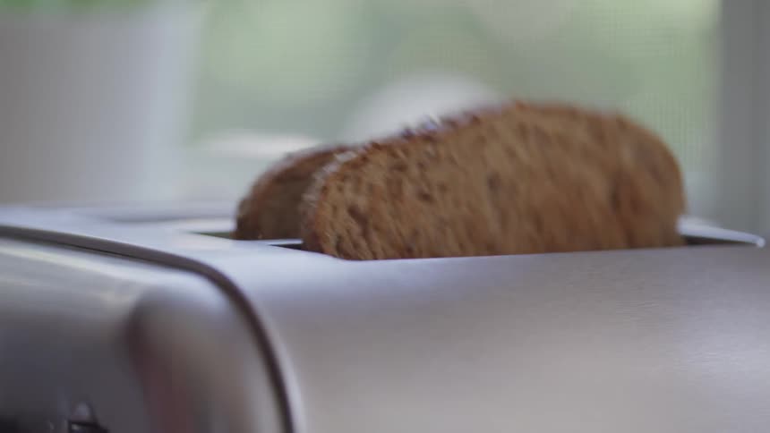 Two pieces of cooked toast pop out of a toaster