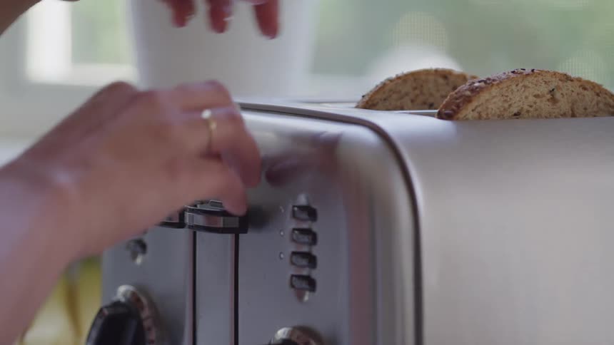A person puts two slices of bread into a toaster and turns it on