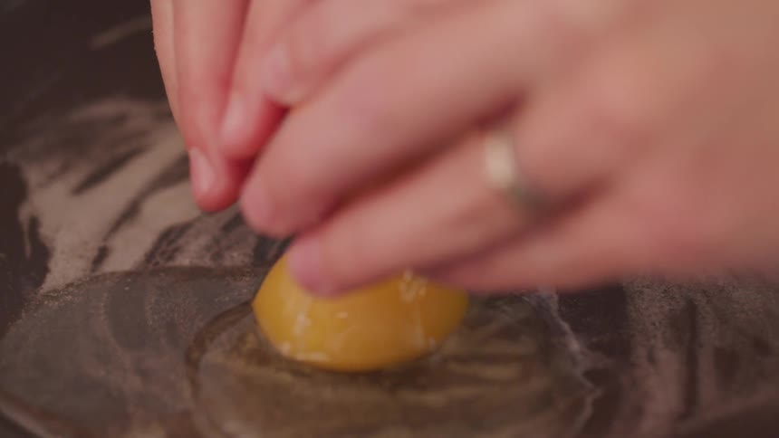 A person cracking an egg on a pan