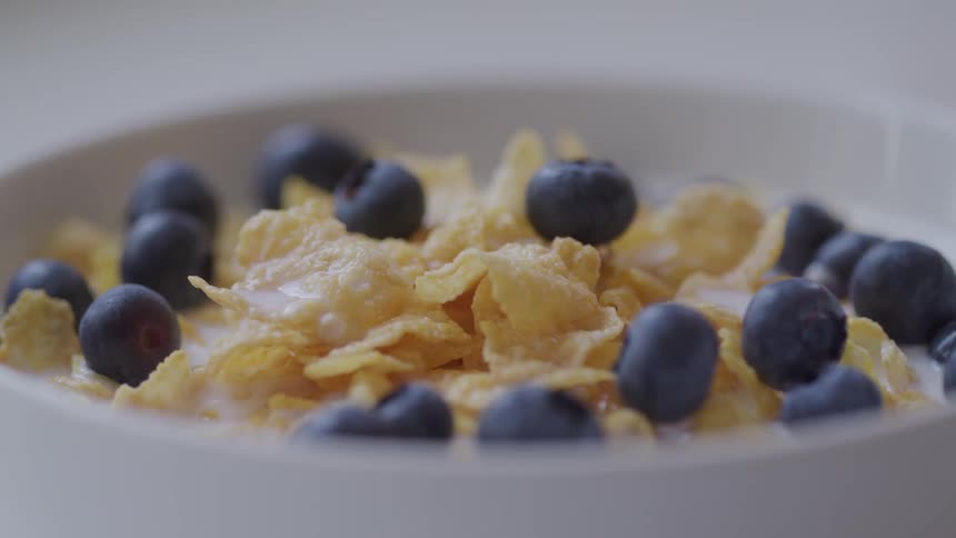 Blueberries are added to a bowl of corn flakes