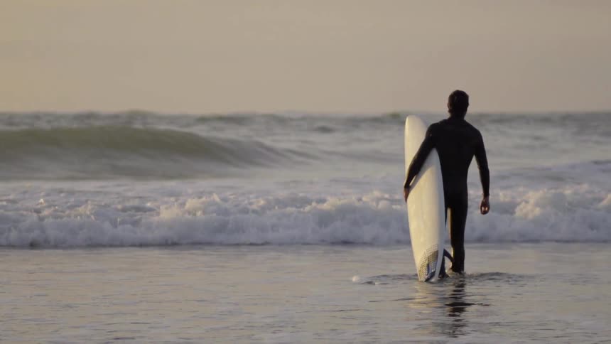 Man surfing a wave on his surfboard in the ocean near the shoreline.