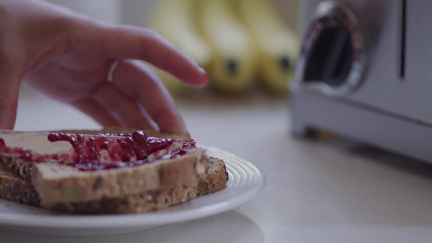 Woman spreads jam on toast