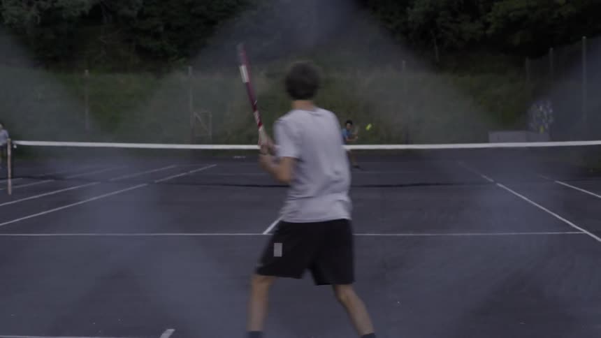 Boy Playing Tennis On Outdoor Court Under Bright Sunny Blue Sky.