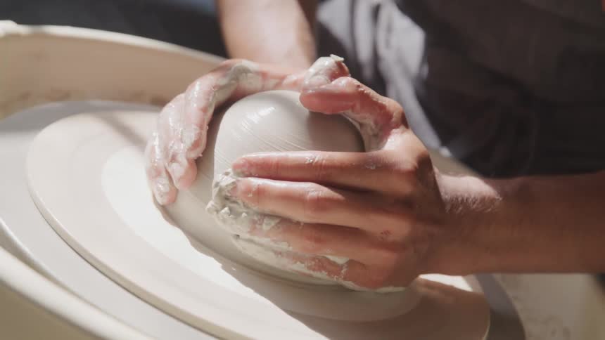 Potter shapes clay on pottery wheel