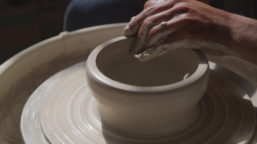 A man is making pottery indoors