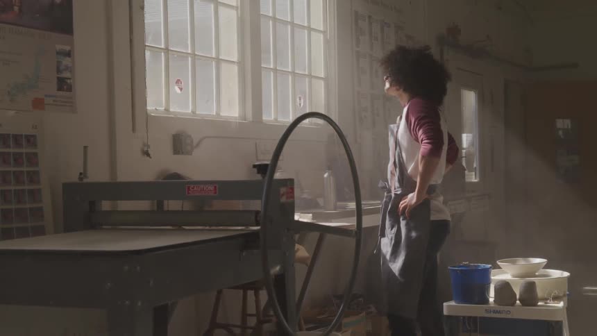 A woman looks out a window in a workshop