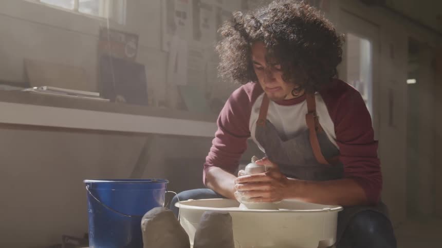 Man works with a clay on a pottery wheel