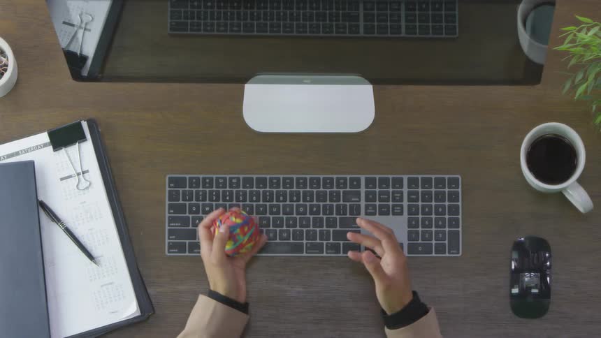 Hands over a desk playing with a rubber band ball
