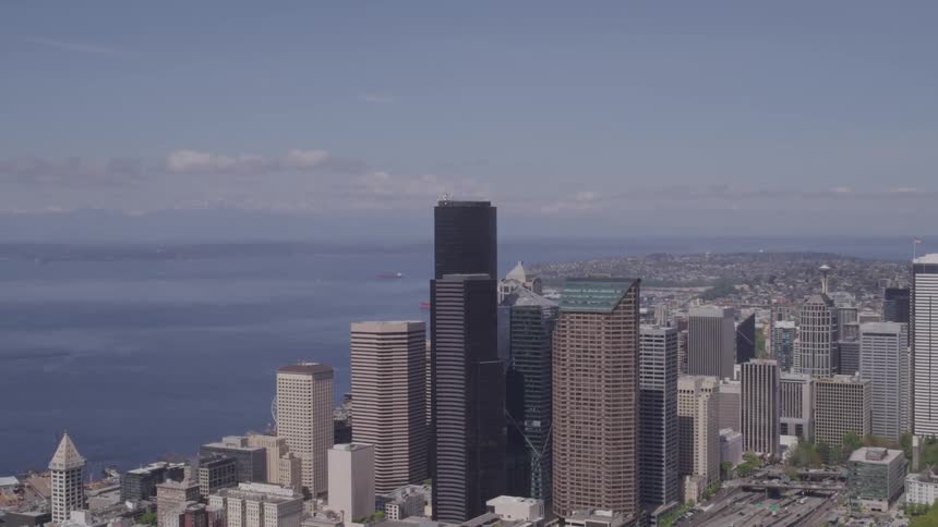 Skyscrapers stand near ocean under slightly clouded sky