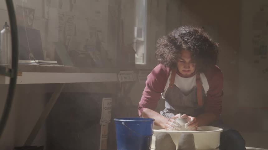 A man is forming clay on a pottery wheel