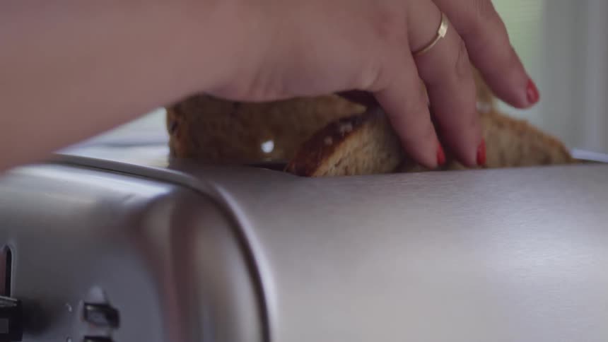 Two slices of toast being placed in a toaster