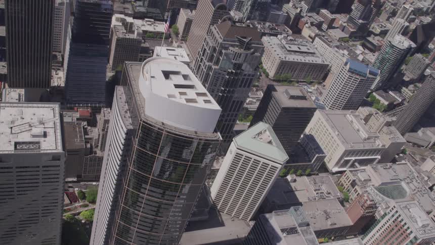 An orbiting aerial view of a skyscraper with the american flag on top