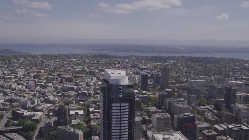 A skyscraper with an american flag surrounded by other buildings