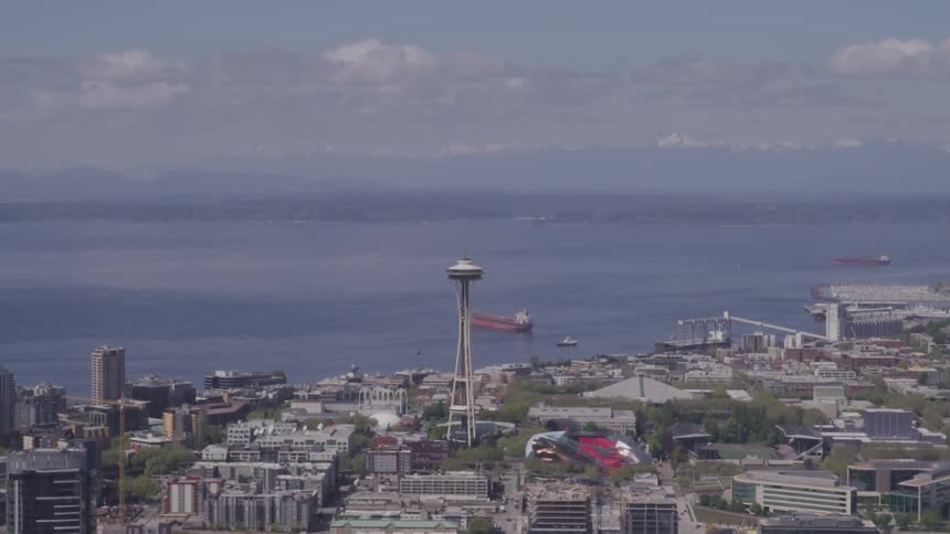 A tall building stands out in an urban area next to the ocean on a cloudy day