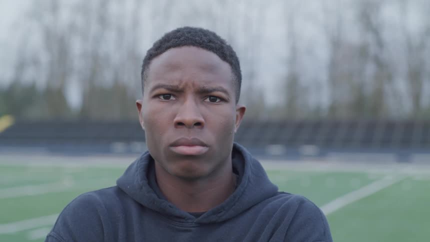A man poses with an angry face while he stands on a football field