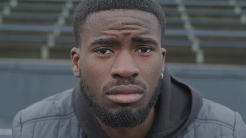 A man in a jacket looks at the camera