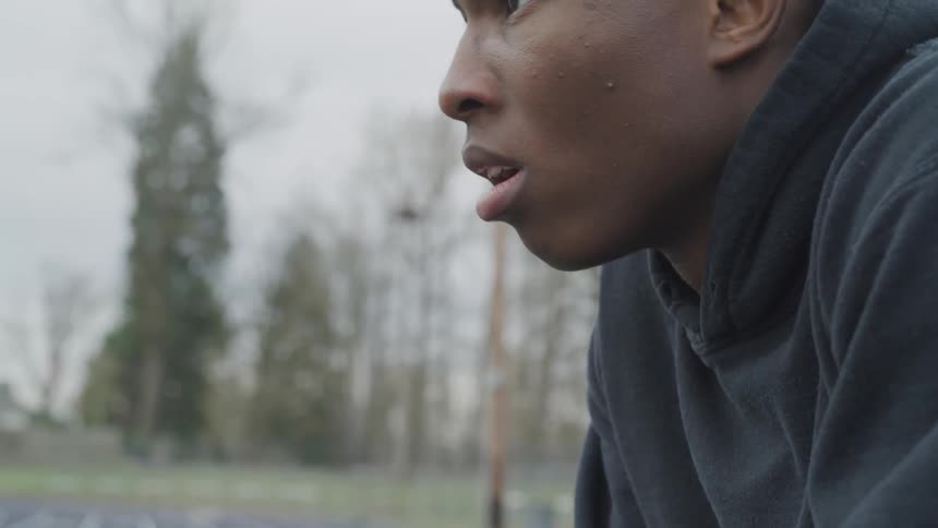 A young black man lifts his face up and looks into the distance