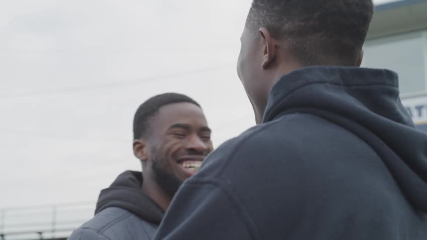 Two african american males greeting other and hugging