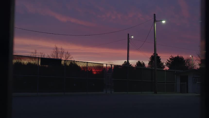 The sun setting behind a fenced in area