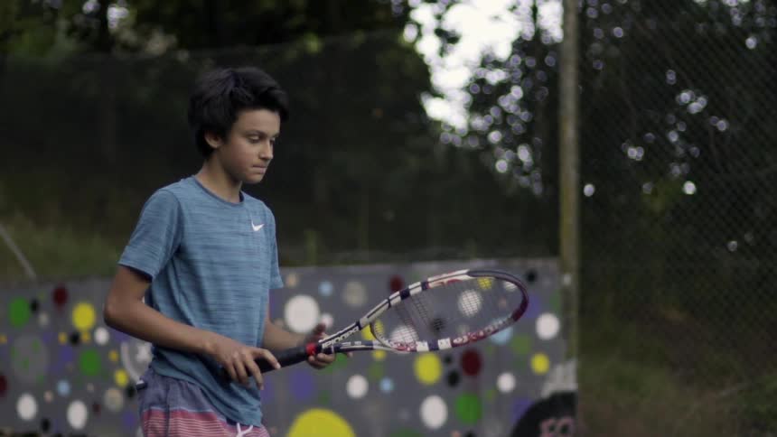 Young Kid Playing Tennis Outdoors on Court Under Sunny Day — Sports Footage Clip.