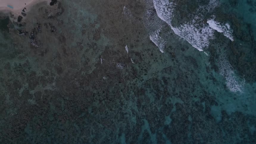 Passing over clear ocean water and waves near homes on shore