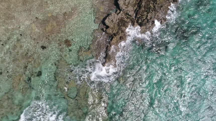 An aerial view of waves crashing along the rocks on the coast