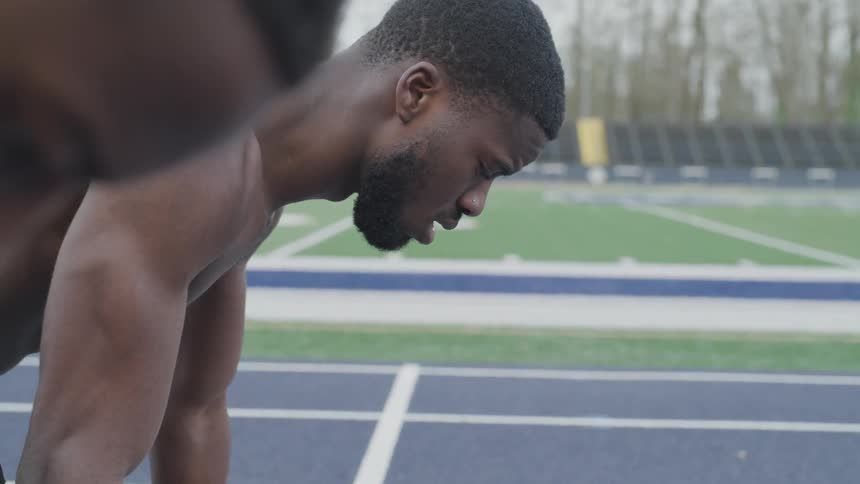 Two men in position at the start line of an outdoor track