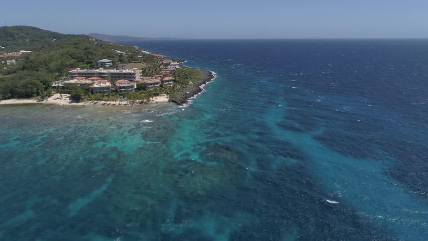 Buildings on a headland extending into a blue ocean