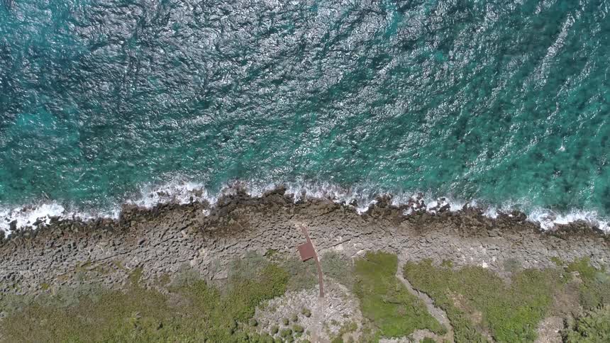 Wind blows the ocean waves which splash and crash into foam upon a rocky shoreline