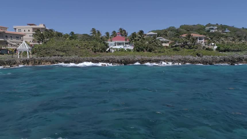 Camera moves over the water towards a house built on a coast