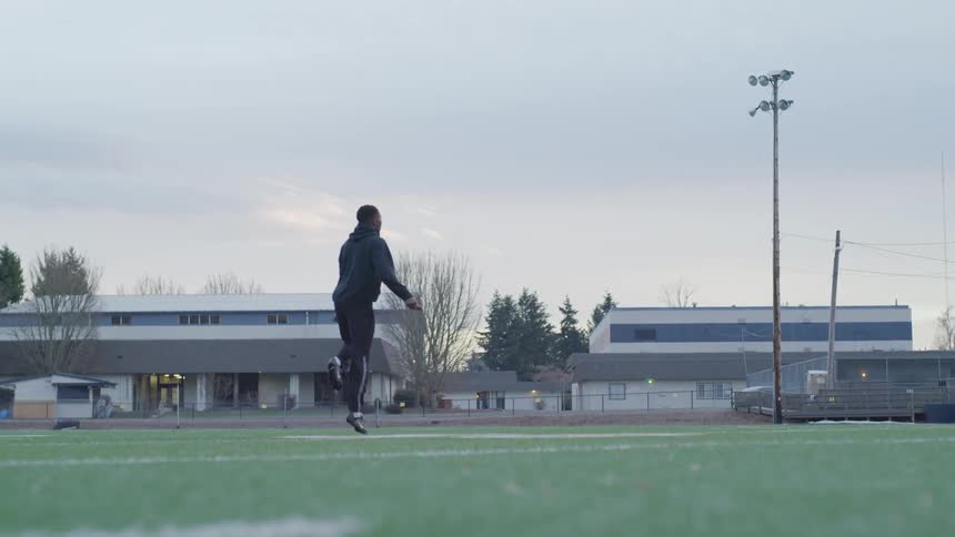 A man jumps rope while next to a track outdoors