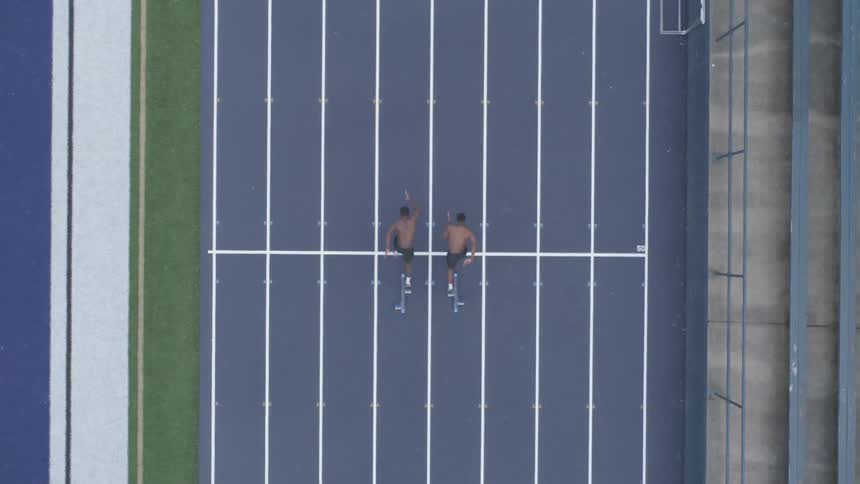 Two men are running outdoors on a track